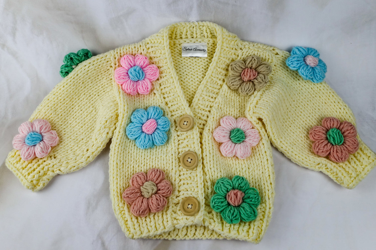 Yellow knitted cardigan with floral patterns on a white background